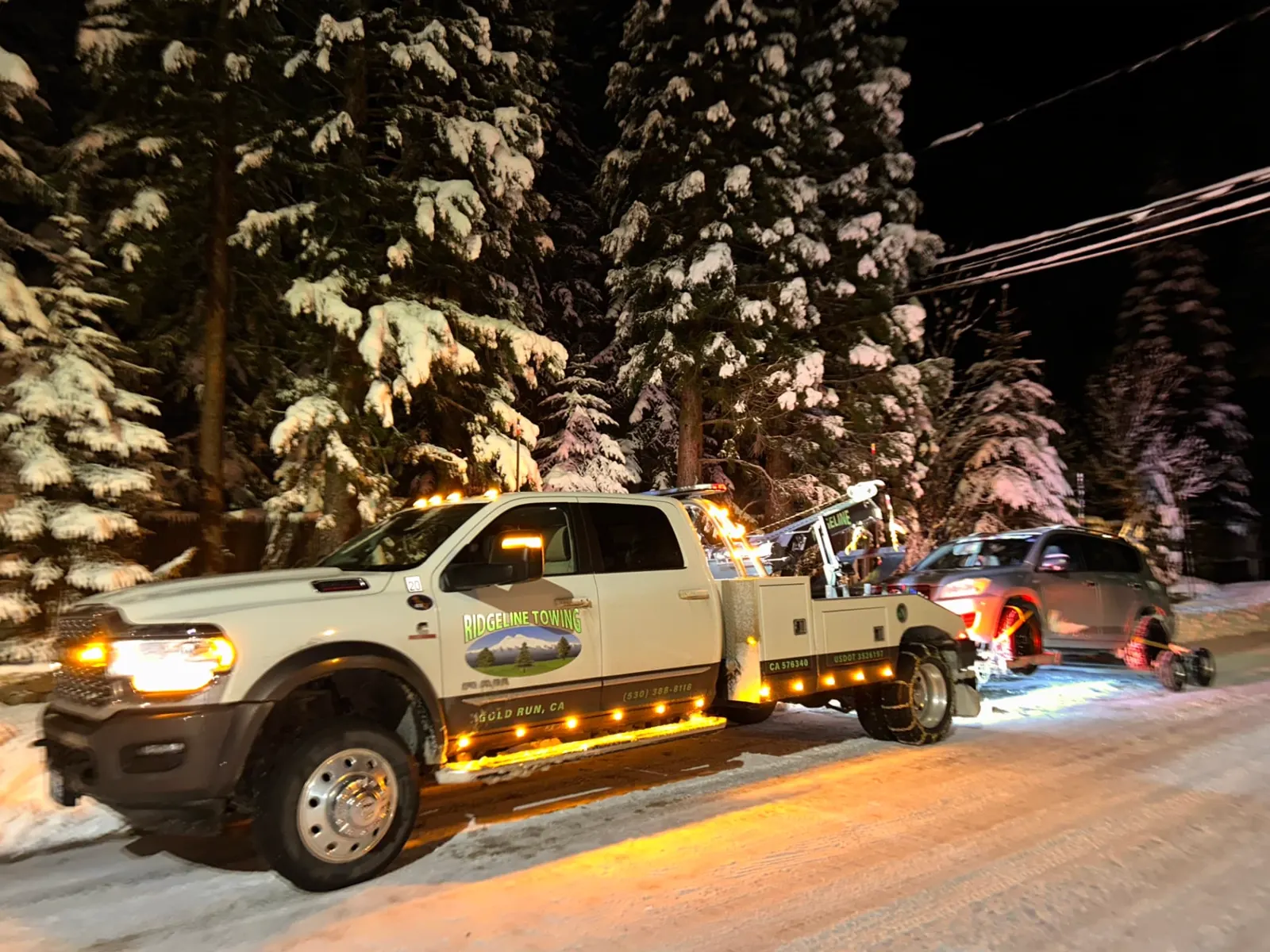 Ridgeline Towing wrecker towing an SUV on a snow-covered road at night near Gold Run, California